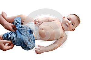 A mother woman puts on jeans pants for a baby boy, isolated on a whit