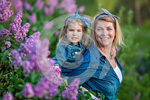 Mother woman with two cute smiling girls sisters lovely together on a lilac field bush all wearing stylish dresses and