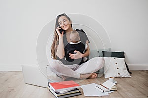Mother working at home with baby in ergo backpack