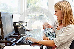 Mother working in home office with baby