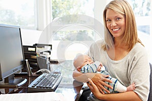 Mother working in home office with baby