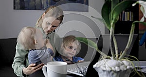 Mother working from home. using laptop at desk with kids on her lap