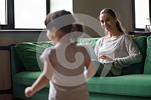 Mother working on laptop while kid girl playing at home