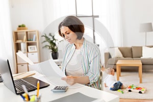 Mother working with papers and baby boy at home