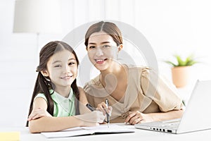 Mother is working and teaching her daughter doing home work