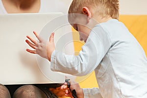 Mother working using laptop, little boy disturbing