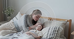 Mother worried son health check hot forehead lying on bed pillow. Preschooler feeling head pain ache