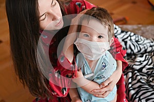 A mother worries about her sick child. Portrait of a young child measuring temperature. masked child