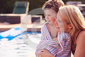 Mother Wrapping Son In Towel By Outdoor Swimming Pool On Summer Vacation