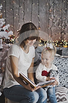 Mother year-old daughter read the book in Christmas decorations
