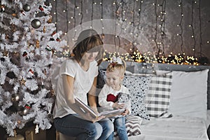 Mother year-old daughter read the book in Christmas decorations