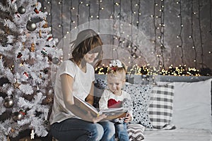 Mother year-old daughter read the book in Christmas decorations
