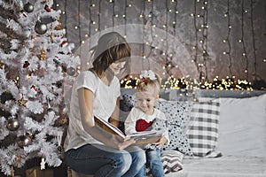 Mother year-old daughter read the book in Christmas decorations