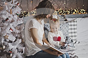 Mother year-old daughter read the book in Christmas decorations