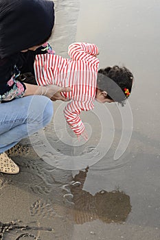 Mother and young child at beach playing with water