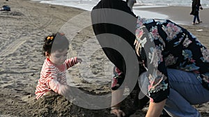 Mother and young child playing with sand at beach