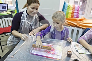 Mother with young daughter learning to make ebru drawing in workshop