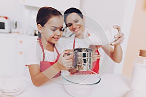 Mother and Young Daughter Percolate Flour for Cake