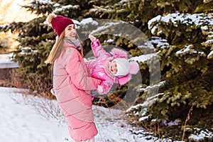 Mother and young daughter in pink whirl in winter near Christmas trees