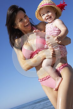 Mother With Young Daughter Running Along Beach Together