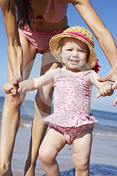 Mother With Young Daughter Walking Along Beach Together