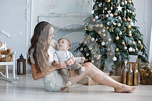 Mother and young son at home near Christmas tree
