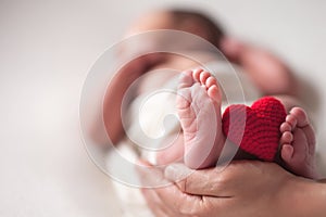 Mothercare newborn concept. Mother holding baby feet and heart