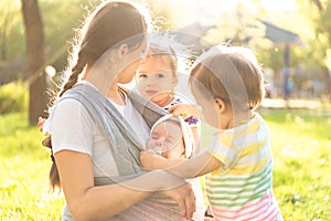 Motherhood, care, infants, summer, childhood and large families concept - Young beautiful mom with newborn baby in sling