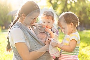 Motherhood, care, infants, summer, childhood and large families concept - Young beautiful mom with newborn baby in sling