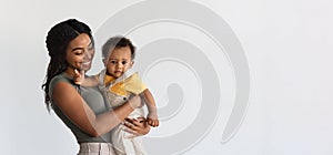 Motherhood Concept. Smiling Young Black Mother Holding Adorable Infant Son On Arms