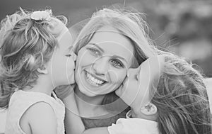 Motherhood. Daughters kiss mother on natural landscape