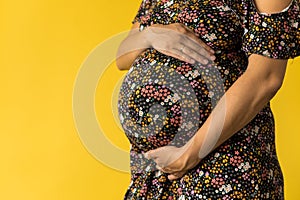 Motherhood, femininity, love, care, waiting, hot summer - bright croped Close-up unrecognizable pregnant woman in floral