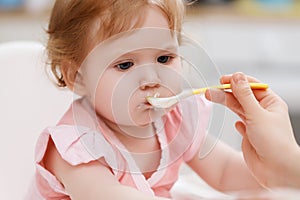 Motherhood and health . Baby& x27;s health and healthy food . Mother feeding her baby girl with spoon. Mother