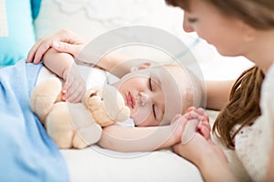 Motherhood. Parenthood. Young mother looking at her baby sleeping in bed