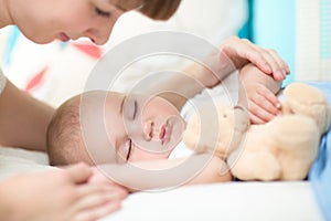 Motherhood. Parenthood. Young mother looking at her baby sleeping in bed