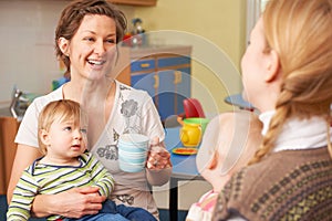 Mothers With Babies Chatting And Drinking Coffee At Playgroup