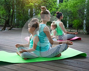 Mothers and daughters doing exercise practicing yoga outdoors