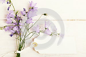 Mothers day card with with a bouquet of delicate wildflowers campanula on white wooden board