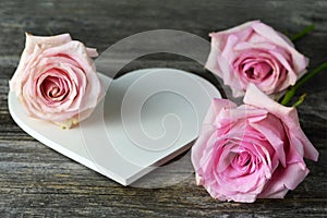 Mothers Day card. White wooden heart shaped decoration and pink roses