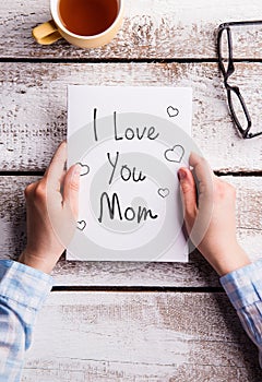 Mothers day composition. Hands holding note. Studio shot.