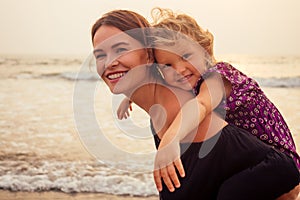 Mothers Day concept of love, parenthood and a happy family. Mother and child daughter having fun at sunset on beach
