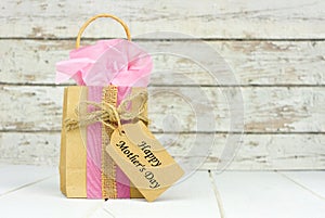 Mothers Day gift bag with tag against rustic white wood