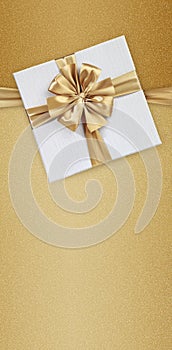 Mothers day gift card, white box wrapped with golden ribbon bow isolated on beige glittering background with copy space, top view