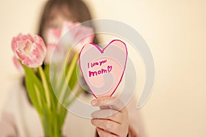 Mothers Day. girl with tulips and heart card.Pink heart card and pink tulips close-up in the hands of a girl.moms day