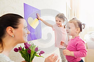 Mothers day, girls giving flowers and card to their mum