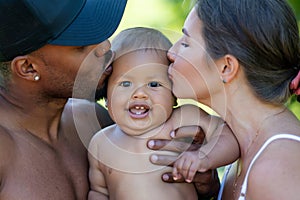 Mothers and father kissed Biracial baby. kissing baby. Mother kiss child, father caring baby. Closeup face of
