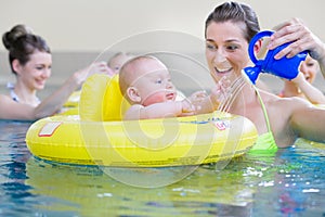 Mothers and kids having fun together playing with toys in pool