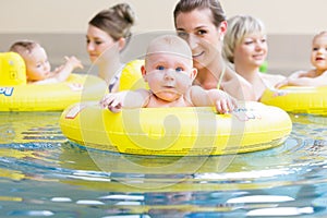 Mothers and kids having fun together playing with toys in pool