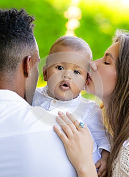 Mothers kissed baby. Close up portrait of mother kissing multiracial baby. Mother kiss child, father caring baby