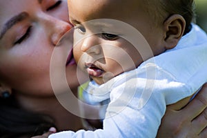 Mothers kissed baby. Close up portrait of mother kissing multiracial baby. Mother kiss child, macro. Closeup face of